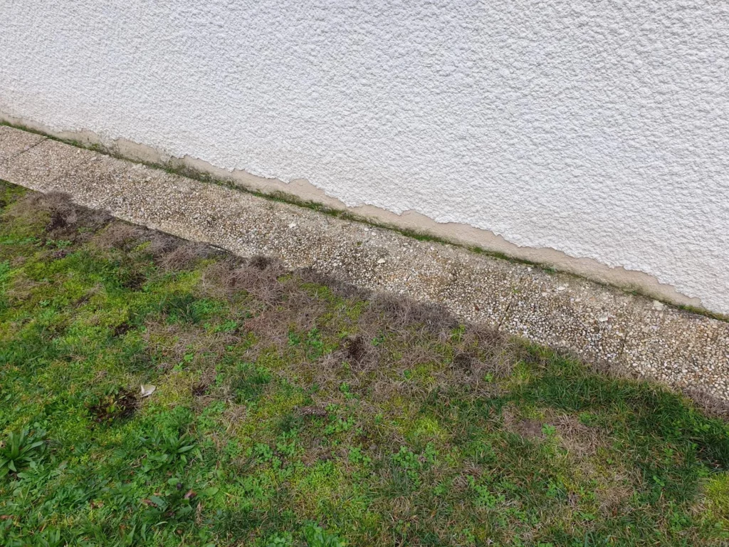 Pied de mur enduit à la chaux taché par les rejaillissements, avant pose de plinthe